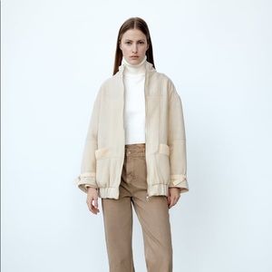 High collar bomber jacket with long sleeves with adjustable belts. Front pockets